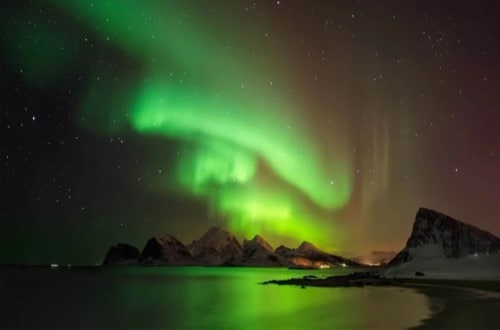 Aurora borealis above snowy island Vestvagoya Lofoten on Norway Voyages. Travel with World Lifetime Journeys